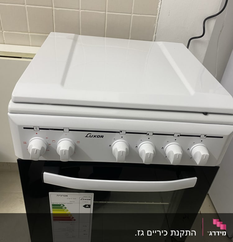 תנור לבן עם כפתורים ומדבקת דירוג אנרגיה